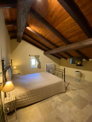 Un dormitorio con una cama grande en una habitación con techos de madera. en Tenuta Folesano Wine Estate 13th century, en Marzabotto