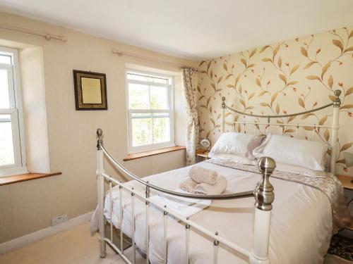 a bedroom with a white bed and two windows at The Ark Cottage in Par