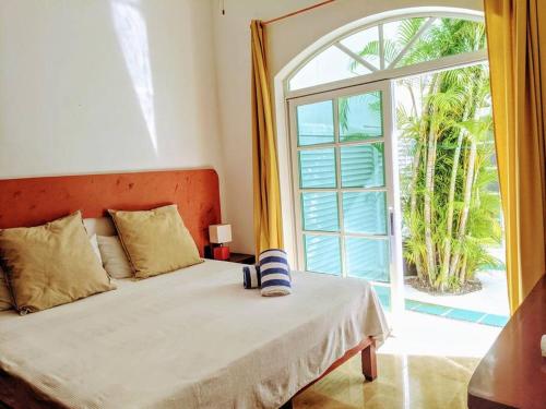 Un dormitorio con una cama y una ventana grande en 9br 6ba Large groups! Best location in town Walk to beach, 5th ave Cozumel ferry, shopping, nightlife! Roof plunge pool!! Castillo Playacar Fase 1 25max, en Playa del Carmen