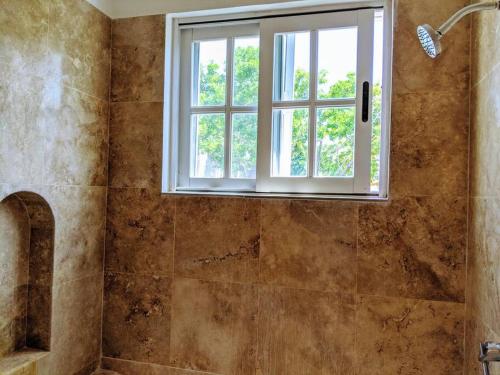 Un baño con ducha y ventana. en 9br 6ba Large groups! Best location in town Walk to beach, 5th ave Cozumel ferry, shopping, nightlife! Roof plunge pool!! Castillo Playacar Fase 1 25max, en Playa del Carmen