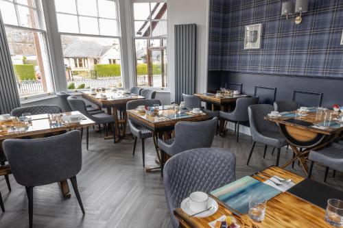 un comedor con mesas, sillas y ventanas en Aye Stay en Inverness