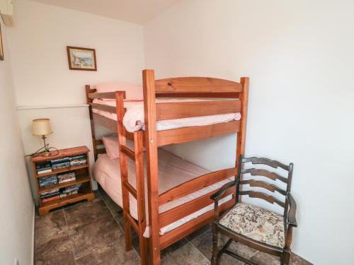 a bedroom with two bunk beds and a chair at The Calf House in Boosbeck