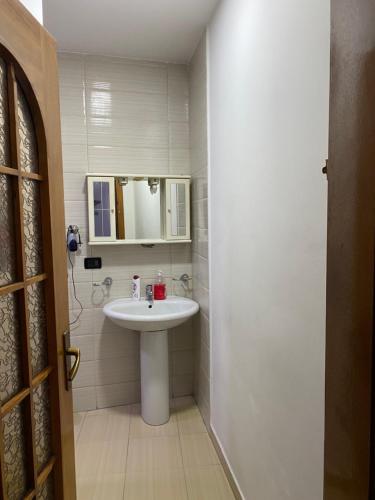 uma casa de banho com um lavatório e um espelho em Tirana Apartment white em Tirana