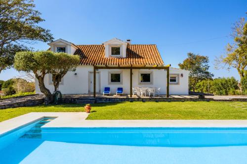 a villa with a swimming pool in front of a house at Quinta do Arneiro in Azeitao
