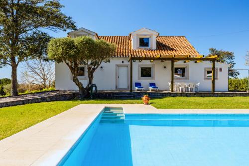 a villa with a swimming pool in front of a house at Quinta do Arneiro in Azeitao