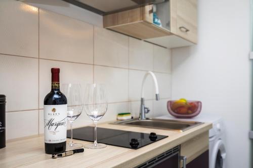 a bottle of wine sitting on a counter with two wine glasses at Studio Apartment PineTree - Mali Lošinj in Mali Lošinj
