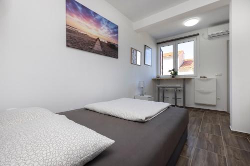 a white bedroom with a bed and a window at Studio Apartment PineTree - Mali Lošinj in Mali Lošinj