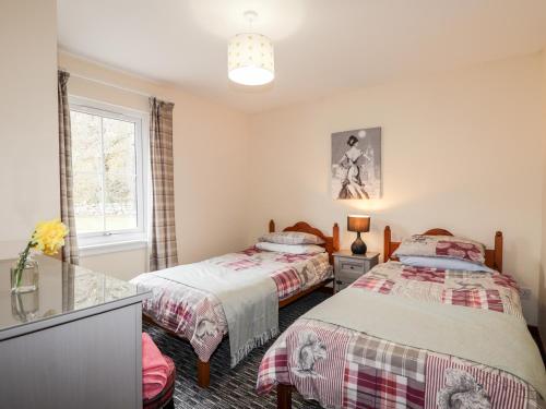 a bedroom with two beds and a window at Stone Water Cottage in Contin