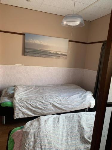 a bedroom with a bed and a painting on the wall at Kurosaki Guesthouse 403 in Kitakyushu