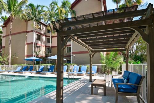 a pool at a hotel with blue chairs next to a building at Sonesta ES Suites Fort Lauderdale Plantation in Plantation