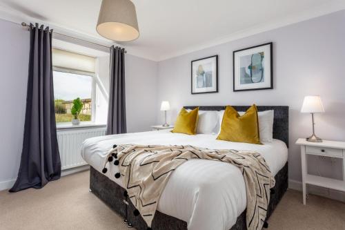 a bedroom with a large bed with yellow pillows at Shore View - Donnini Apartments in Prestwick