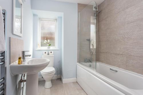 a bathroom with a sink and a toilet and a bath tub at Shore View - Donnini Apartments in Prestwick