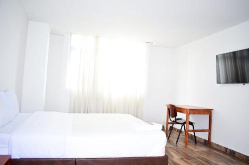 1 dormitorio con cama, escritorio y ventana en Hotel Villa Isabel, en Pasto