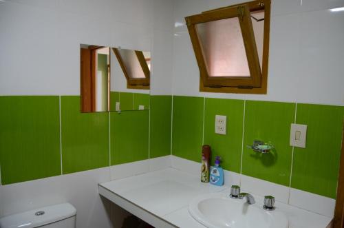 uma casa de banho verde e branca com um lavatório e um WC em Hermoso departamento confortable y estratégico em Sucre