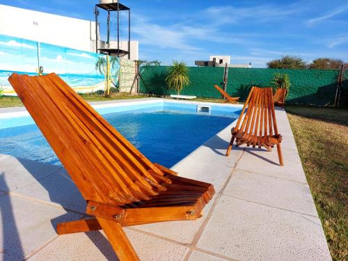 dwa drewniane krzesła siedzące obok basenu w obiekcie Cabaña Sarita w mieście Santa Rosa