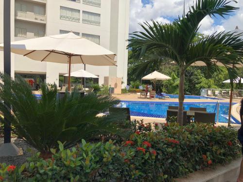 a swimming pool with an umbrella and a hotel at Park Veredas do Rio Quente Flat 518 - Com acesso ao RIO in Rio Quente