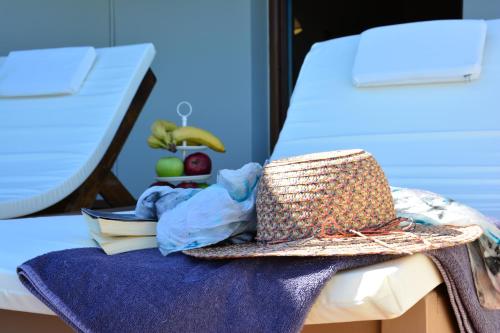 a straw hat sitting on a bed with books and fruit at Elianthos Villas in Vamos