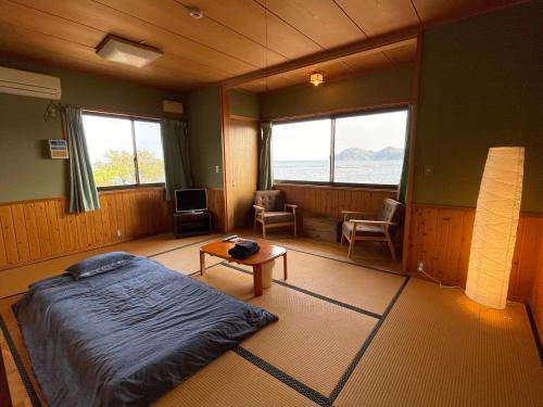1 dormitorio con cama, mesa y ventanas en 大砂荘 OZUNA CAMP and LODGE en Kaiyo