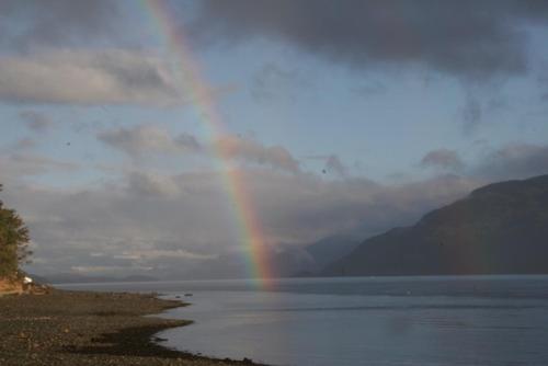 a rainbow in the sky over a body of water at Alert Bay Lodge in Alert Bay