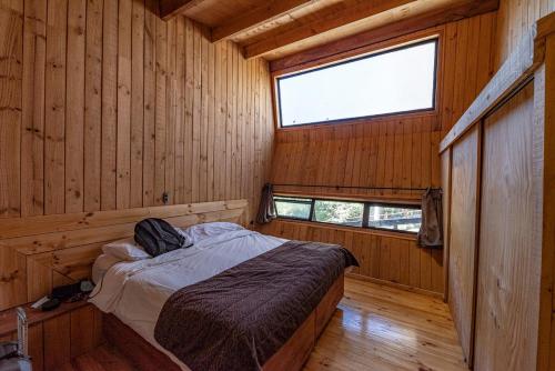 1 dormitorio con 1 cama en una cabaña de madera en Cabaña en el bosque de las Trancas, en Las Trancas