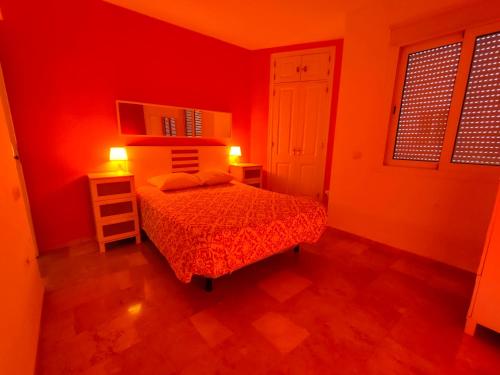 een rode slaapkamer met een bed en twee lichten aan bij Penthouse Near The Beach in Fuengirola