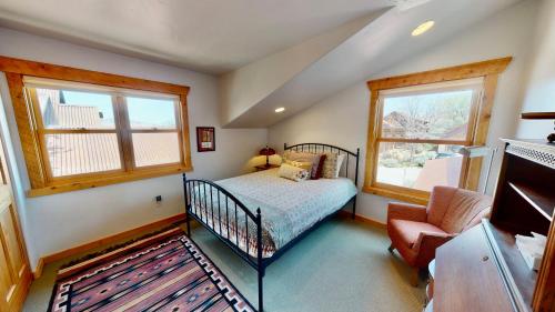 ein Schlafzimmer mit einem Bett, einem Stuhl und zwei Fenstern in der Unterkunft Rim View Retreat #14 in Moab