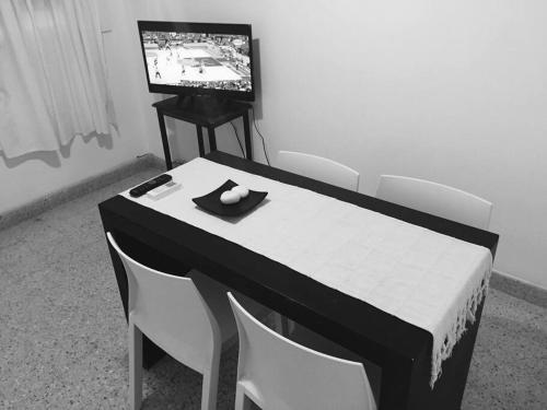 mesa en blanco y negro con sillas y TV en Alojamiento Centrico Bahia Blanca en Bahía Blanca