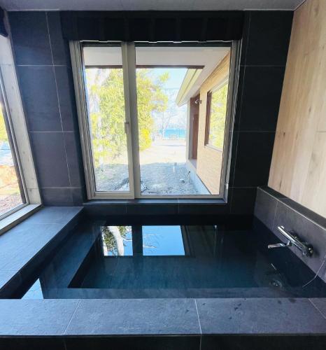 a bathroom with a tub with a window and water at HANA TOYA in Lake Toya