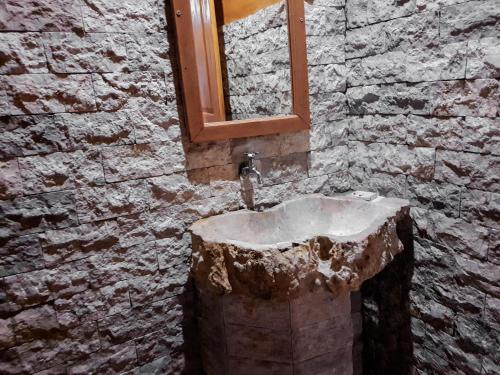 Baño de piedra con lavabo y espejo en Malibu Huts, en Nusa Penida