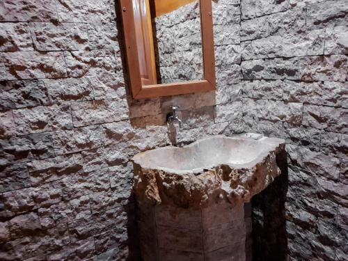 a stone bathroom with a sink and a mirror at Malibu Huts in Nusa Penida