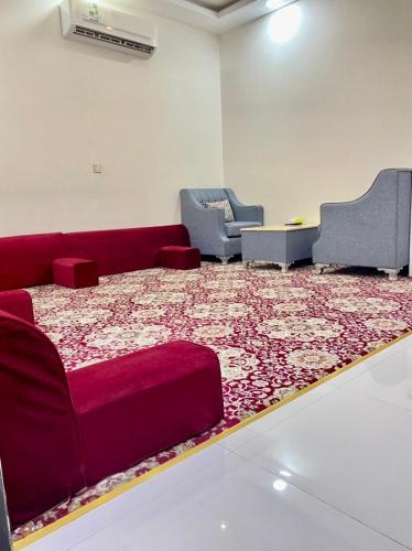 a living room with a red couch and a large rug at شقق باهية نجران للشقق المخدومة in Najran