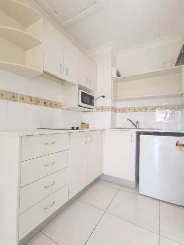 a white kitchen with white cabinets and a microwave at Bay of Palms in Gold Coast
