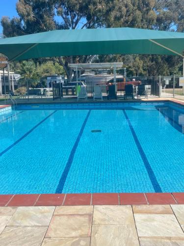 a large blue swimming pool with a green umbrella at Bundalong Riverside Resort in Bundalong