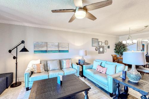 a living room with blue couches and a ceiling fan at Shorewood in Cape Canaveral