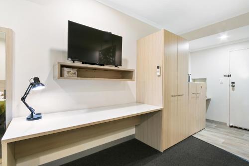 a room with a desk with a tv on a wall at The Aspen & Apartments in Sale