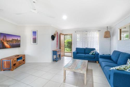 a living room with blue couches and a table at 1 1 Rumbalara Avenue Rainbow Beach in Rainbow Beach
