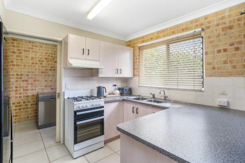 a kitchen with white cabinets and a stove top oven at 1 1 Rumbalara Avenue Rainbow Beach in Rainbow Beach