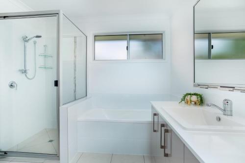 a white bathroom with a tub and a sink and a shower at 25 Cooloola Drive Rainbow Beach in Rainbow Beach