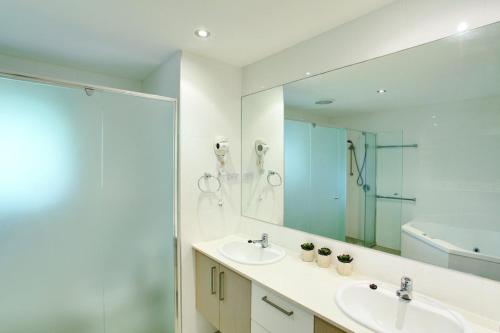 a bathroom with two sinks and a shower and a mirror at 6 Orania Court Rainbow Shores in Rainbow Beach