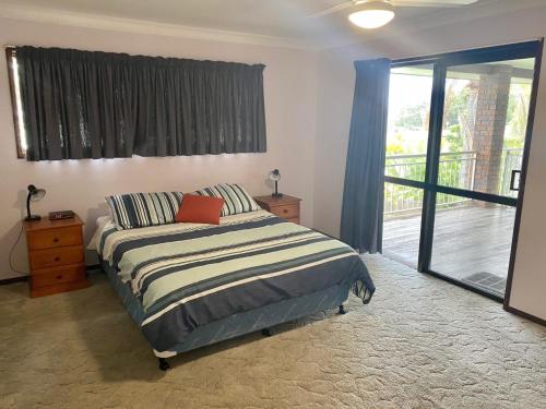 ein Schlafzimmer mit einem Bett und einer Glasschiebetür in der Unterkunft 42 Rumbalara Avenue Rainbow Beach in Rainbow Beach