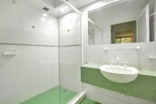 Un baño blanco con lavabo y espejo. en Baden 35 Rainbow Shores, en Rainbow Beach