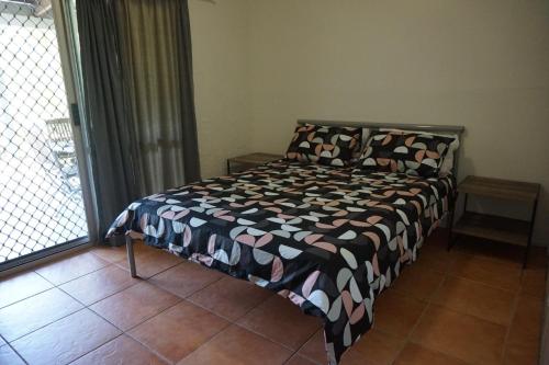 a bedroom with a bed with a black and white comforter at 11 Bomburra Court Rainbow Beach in Rainbow Beach
