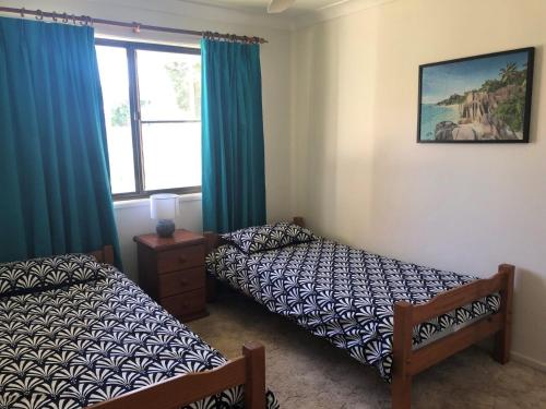 a bedroom with two beds and a window at 10 Coora Court Rainbow Beach in Rainbow Beach