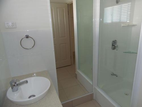 a white bathroom with a sink and a shower at Palmgrove 1 Rainbow Beach in Rainbow Beach