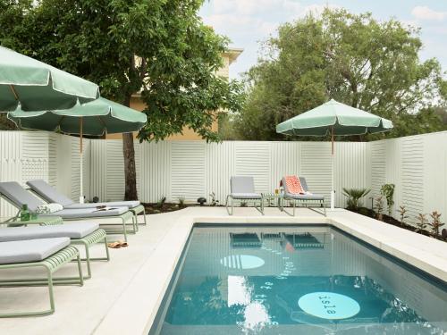 a swimming pool with lounge chairs and umbrellas at The Isla in Batemans Bay