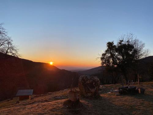 a sunset on a hill with a rock and a tree at Almhaus Kochjosel in Garanas