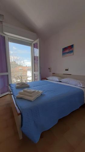 a bedroom with a blue bed with a large window at Hotel Elisabetta 2 stelle in Cattolica