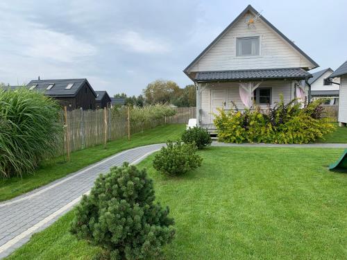 a house with a driveway in a yard at Biale Domki Kopalino in Kopalino