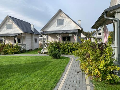 a house with a brick walkway in front of a yard at Biale Domki Kopalino in Kopalino