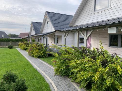a row of houses with bushes in a yard at Biale Domki Kopalino in Kopalino